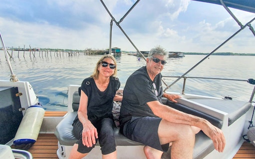 Couple enjoying a boat tour near Kelong structures on a Let's Go Kelong trip.