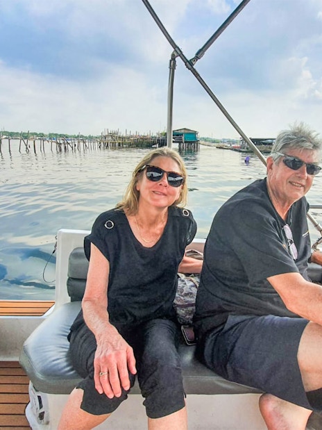 Couple enjoying a boat tour near Kelong structures on a Let's Go Kelong trip.