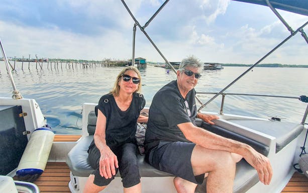Couple enjoying a boat tour near Kelong structures on a Let's Go Kelong trip.