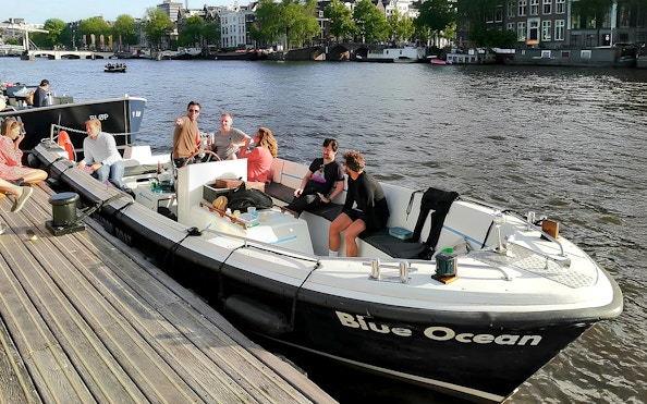 Canal boat with passengers enjoying drinks on Amsterdam's waterways.