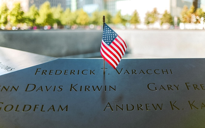 Names engraved at 9/11 Memorial with small American flag, New York City.