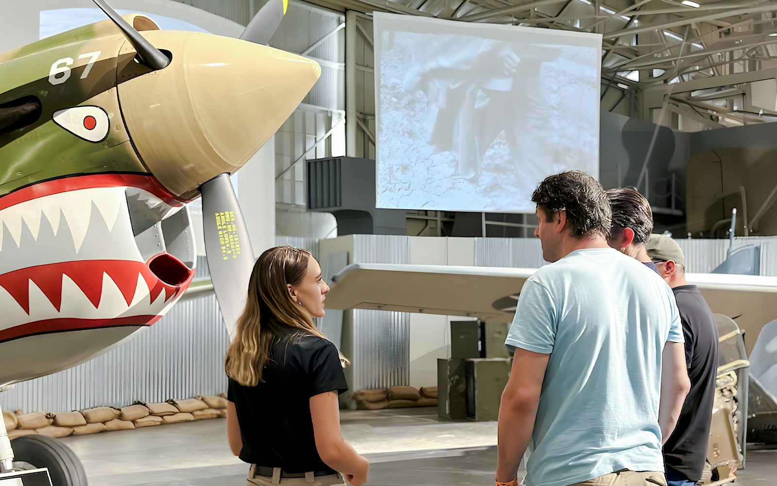 Guests touring Pearl Harbor Aviation Museum near vintage aircraft.