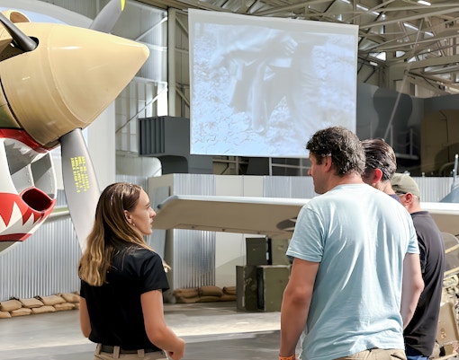 Guests touring Pearl Harbor Aviation Museum near vintage aircraft.