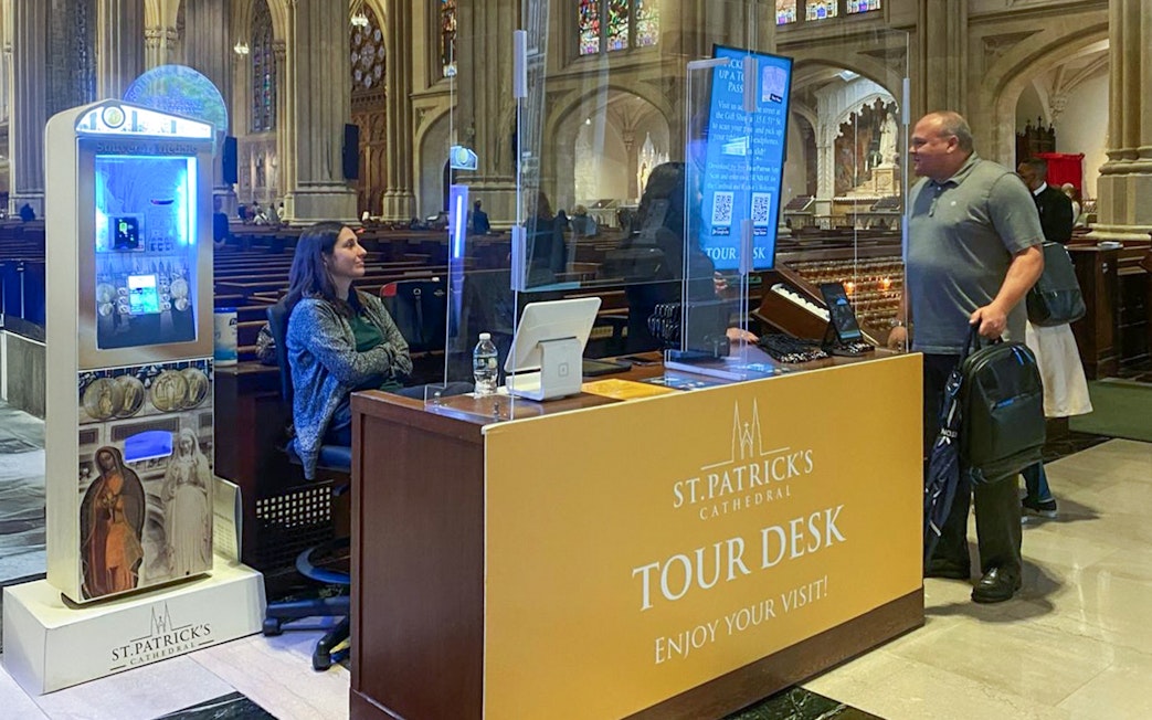 Tour desk inside St. Patrick's Cathedral with visitor and staff interaction.