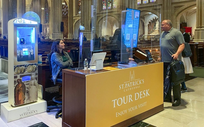 Tour desk inside St. Patrick's Cathedral with visitor and staff interaction.