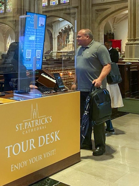 Tour desk inside St. Patrick's Cathedral with visitor and staff interaction.