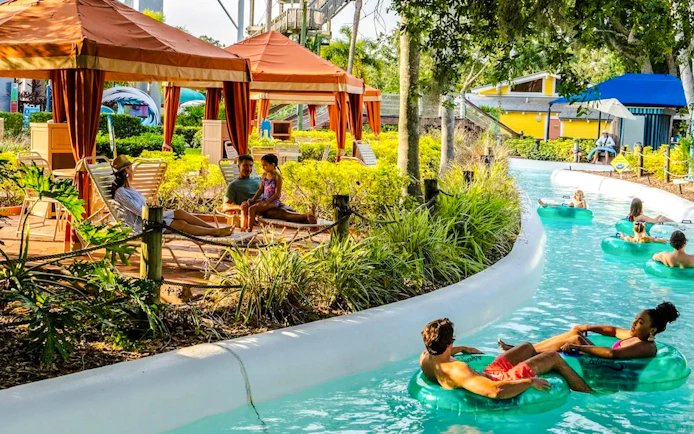 Visitors relaxing in cabanas and floating on a lazy river at Adventure Island, Florida.