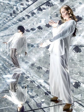 Visitors exploring a mirrored room with reflective surfaces and lights.