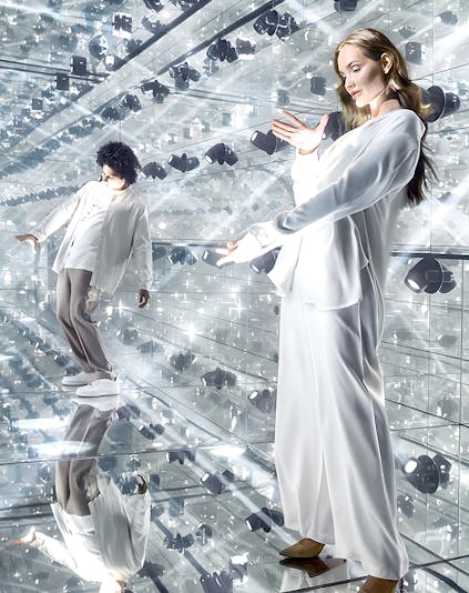 Visitors exploring a mirrored room with reflective surfaces and lights.