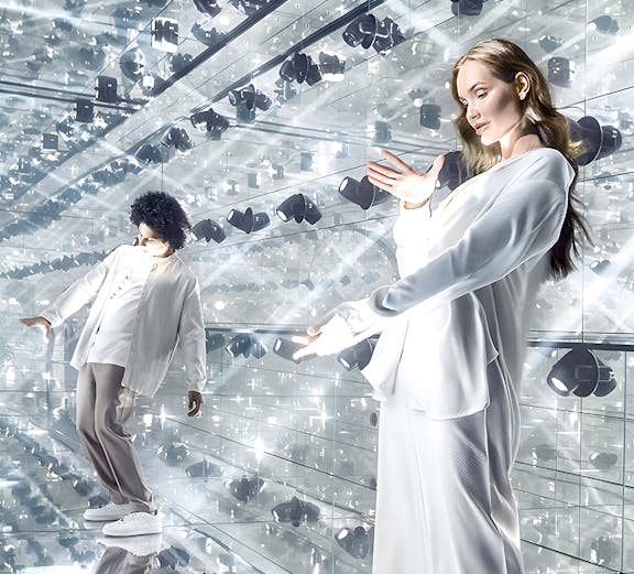 Visitors exploring a mirrored room with reflective surfaces and lights.