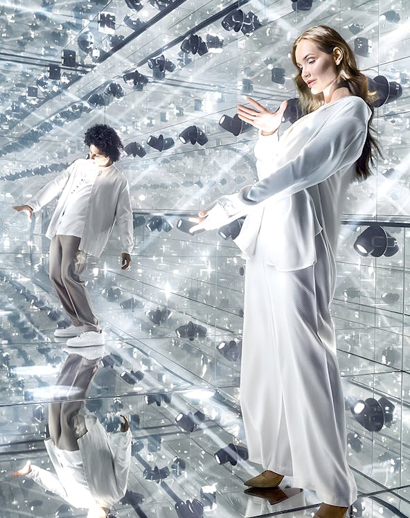 Visitors exploring a mirrored room with reflective surfaces and lights.