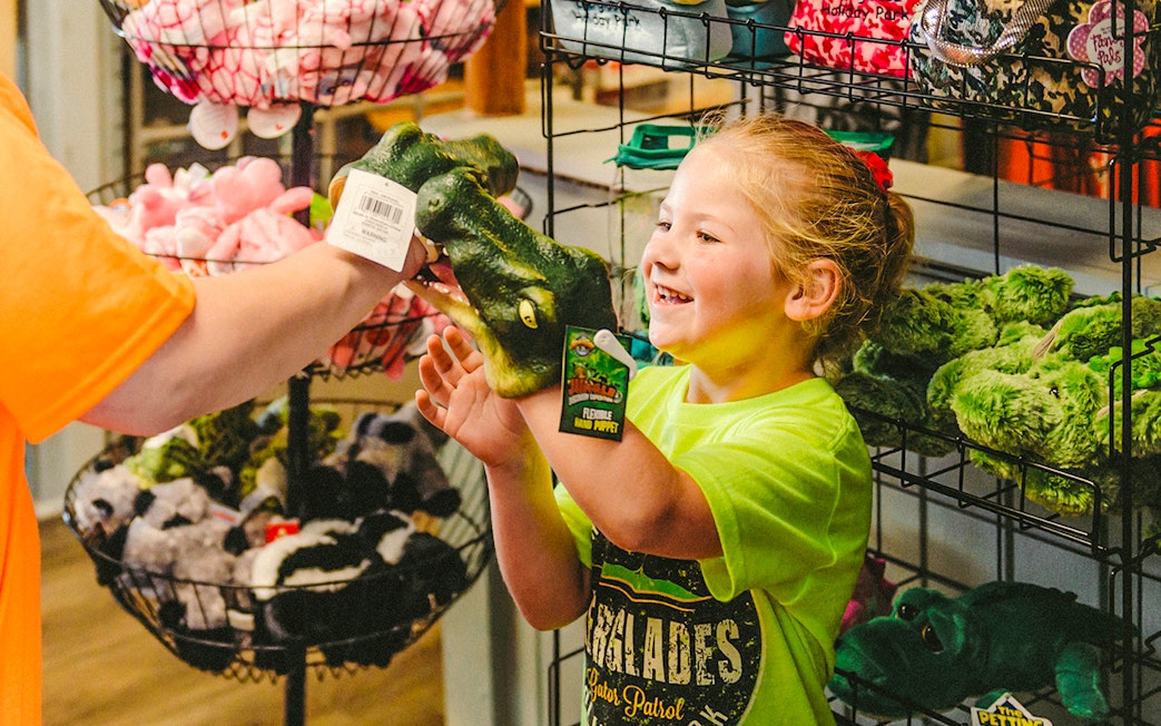 Child holding an alligator puppet at Everglades gift shop during airboat tour.