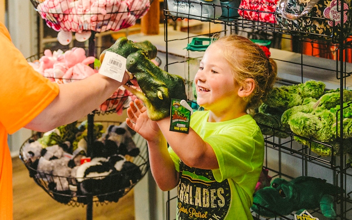Child holding an alligator puppet at Everglades gift shop during airboat tour.