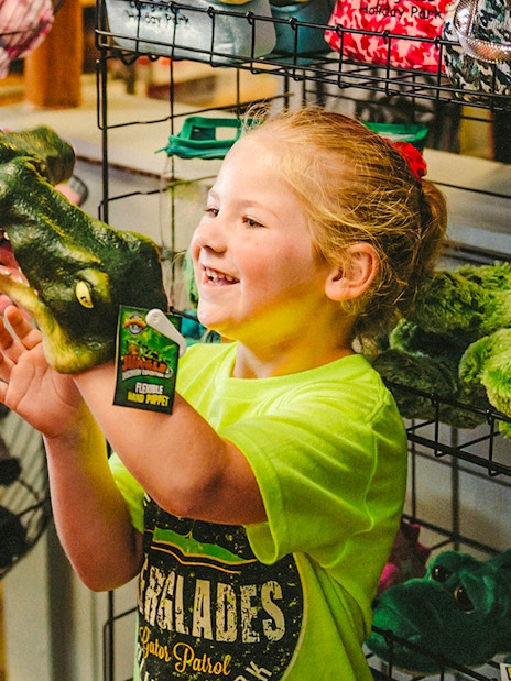 Child holding an alligator puppet at Everglades gift shop during airboat tour.