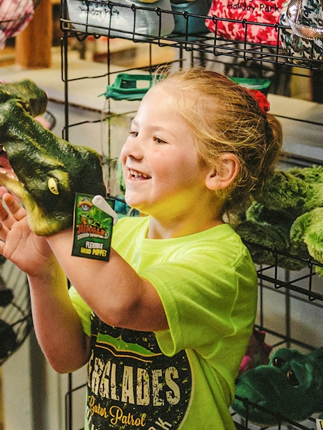 Child holding an alligator puppet at Everglades gift shop during airboat tour.