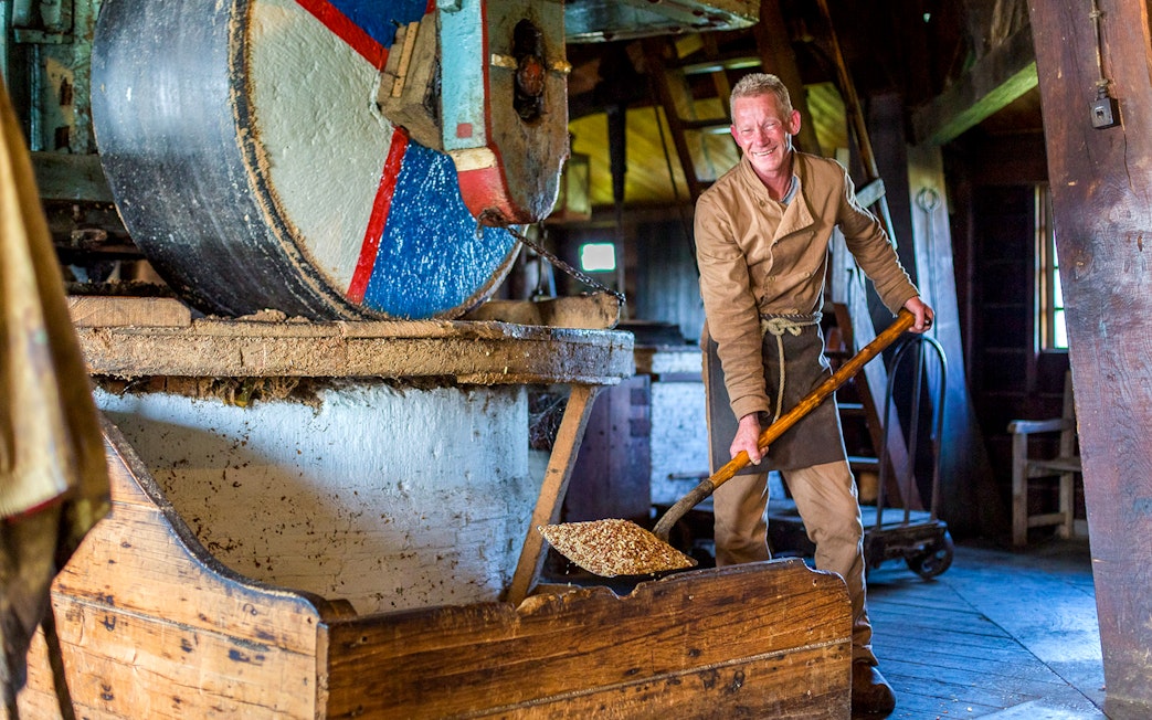 Man operating a millstone inside a traditional windmill.