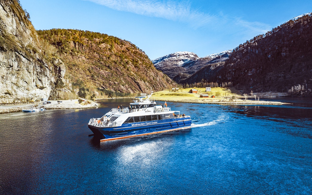 Mostraumen Fjord Cruise boat sailing through scenic fjord with mountains in Norway.