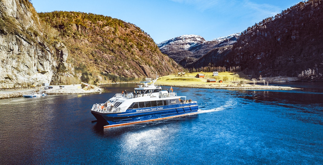 Mostraumen Fjord Cruise boat sailing through scenic fjord with mountains in Norway.