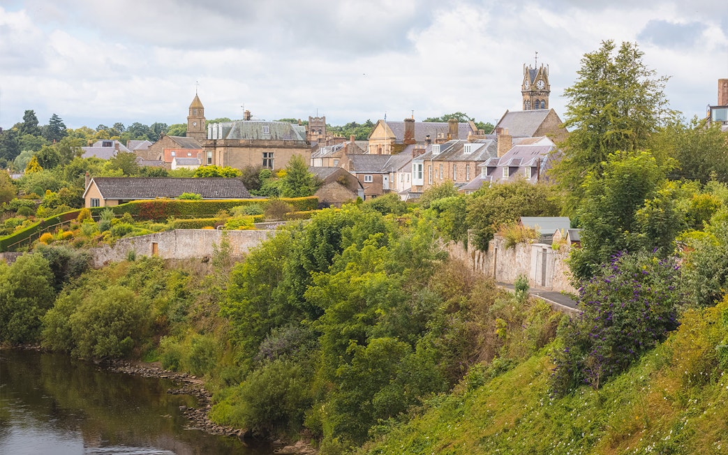 Village Coldstream along River Tweed, Scotland with historic buildings and lush greenery.