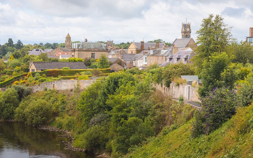Village Coldstream along River Tweed, Scotland with historic buildings and lush greenery.