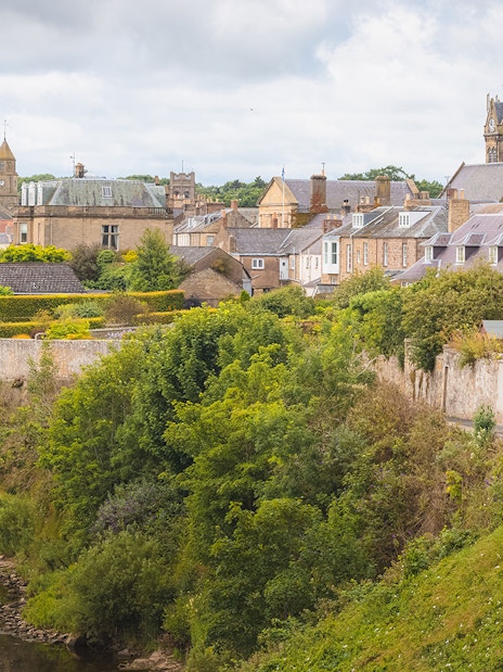 Village Coldstream along River Tweed, Scotland with historic buildings and lush greenery.