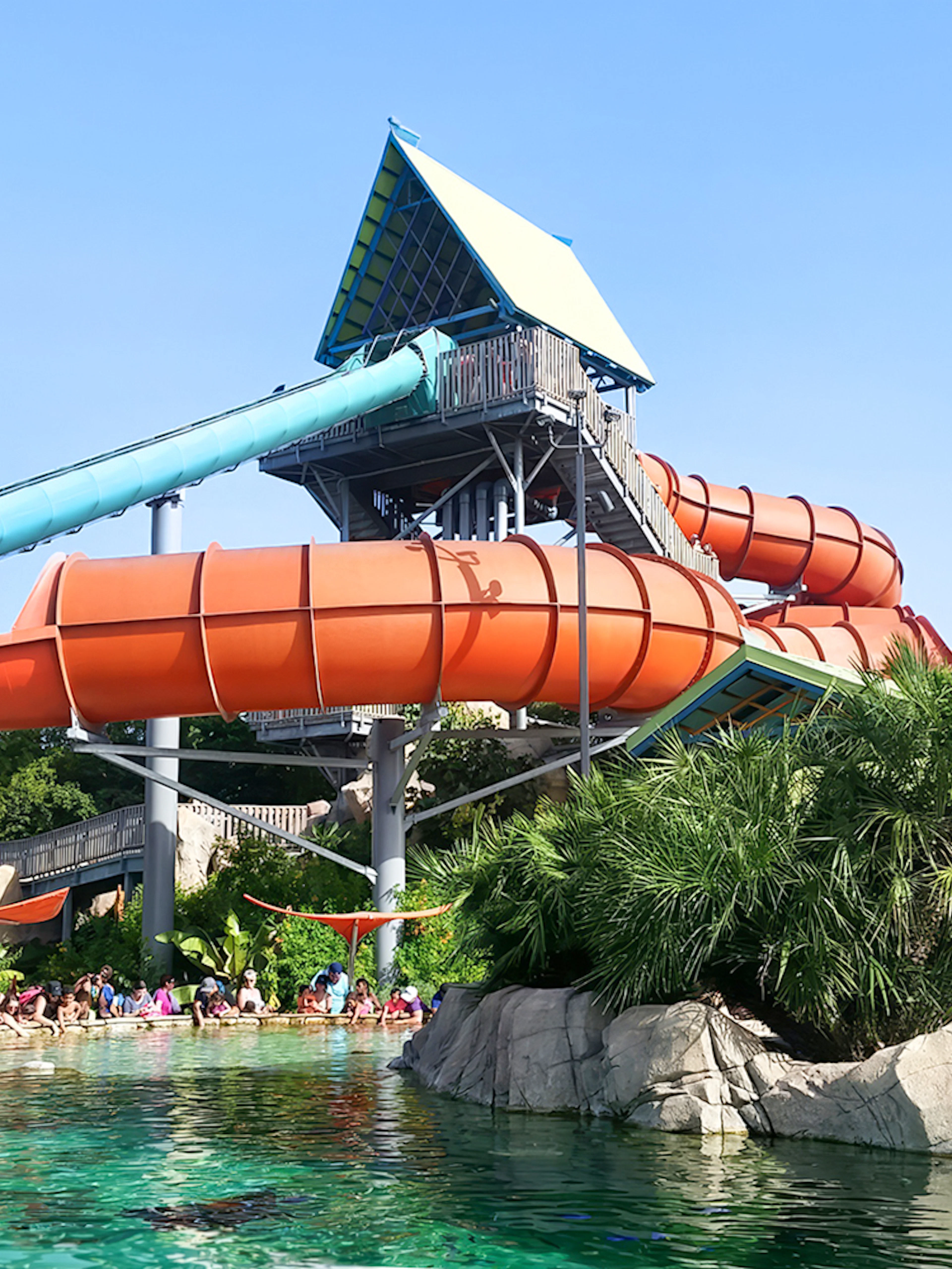 Waterslide at Aquatica San Antonio with people enjoying the pool below.