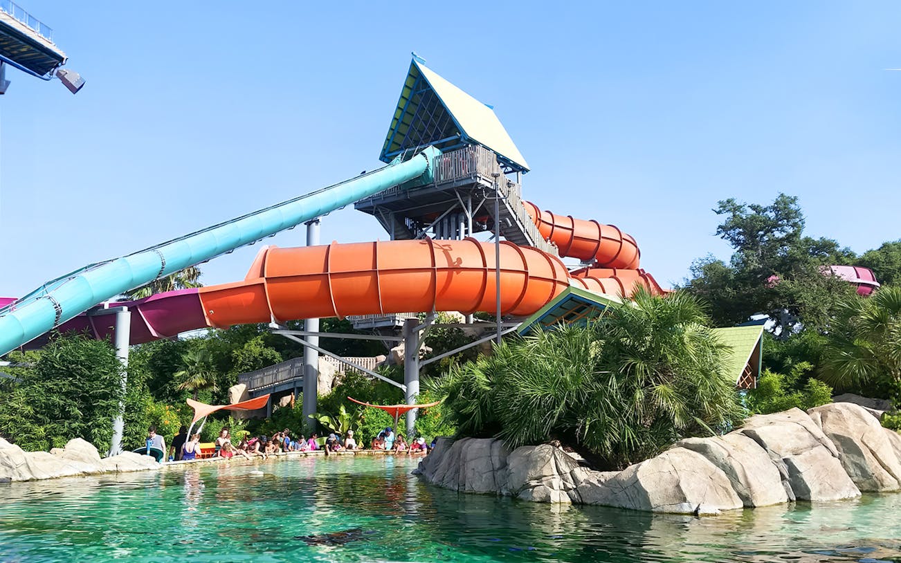 Waterslide at Aquatica San Antonio with people enjoying the pool below.