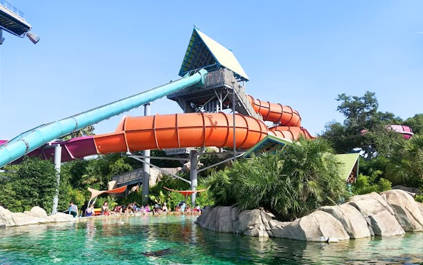 Waterslide at Aquatica San Antonio with people enjoying the pool below.