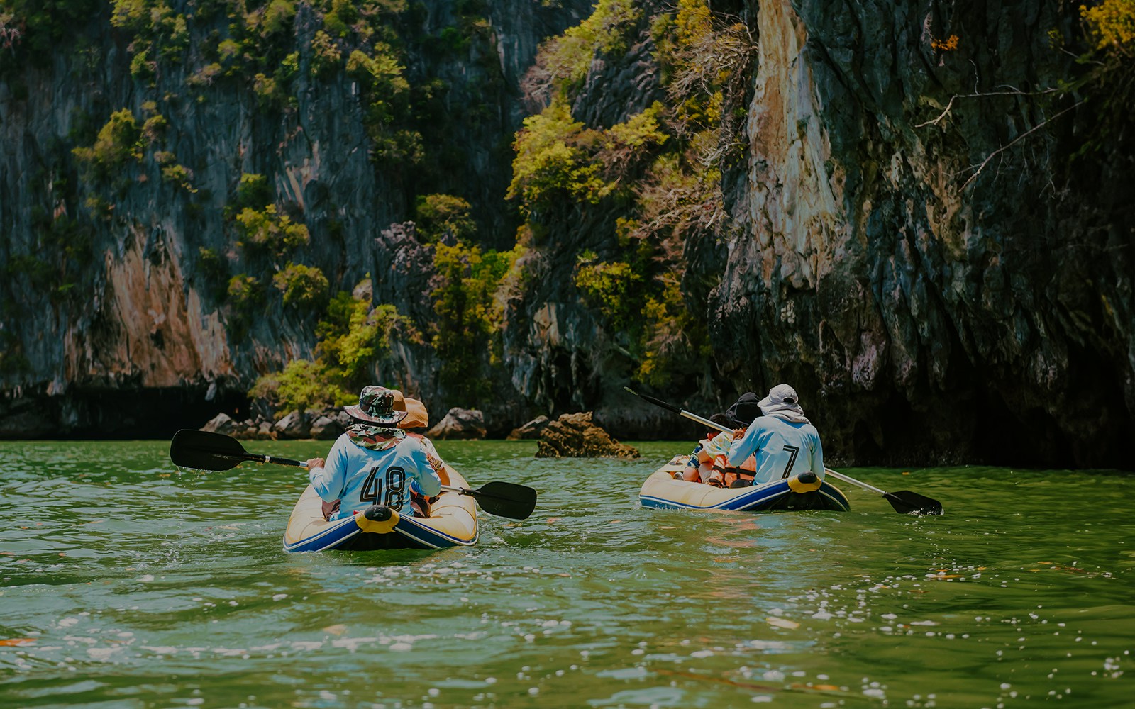 Kayakers paddling near limestone cliffs on James Bond Island tour.