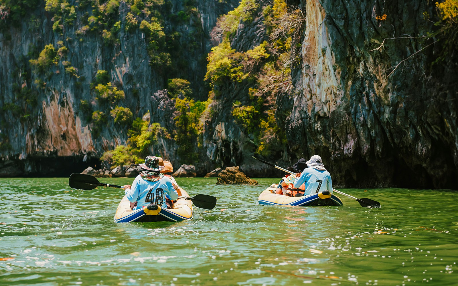 Kayakers paddling near limestone cliffs on James Bond Island tour.