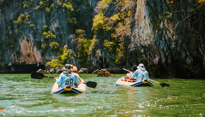 Kayakers paddling near limestone cliffs on James Bond Island tour.