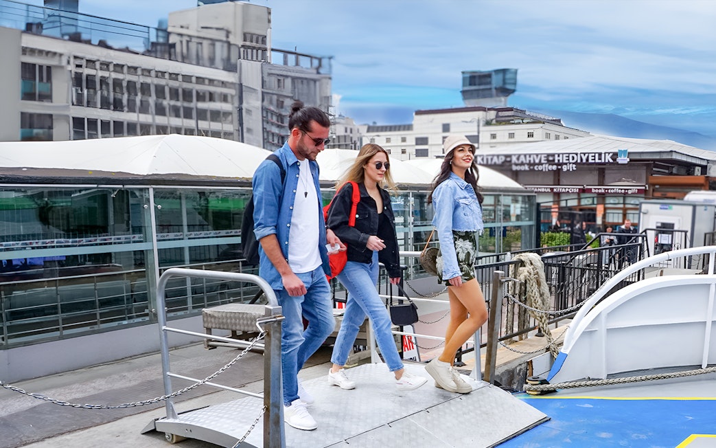 Tourists boarding a Bosphorus cruise ship in Istanbul for an audio guide experience.
