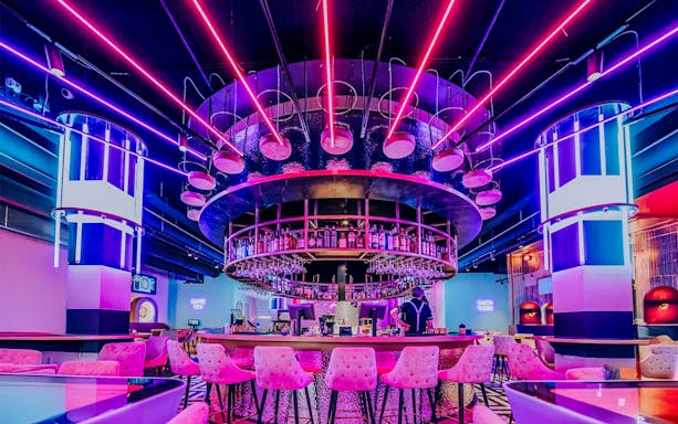 Neon-lit bar interior with circular counter and pink stools, Inside All Out Amsterdam.