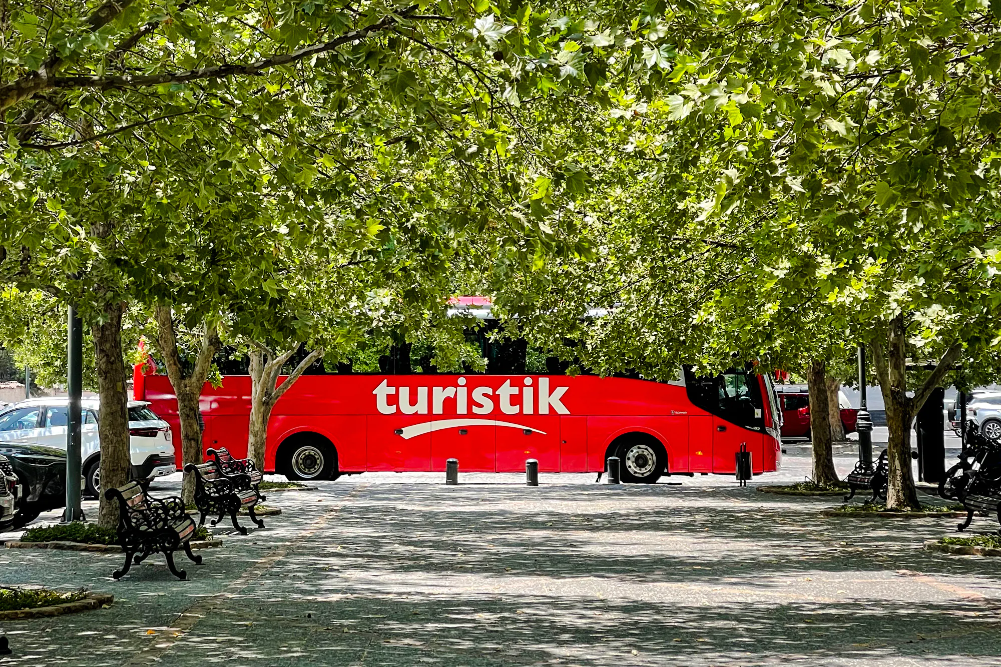 Red tour bus parked under trees in Santiago for Concha y Toro Winery transfer.