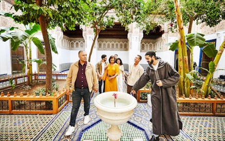 Tourists with a guide in the courtyard of Bahia Palace, Marrakech, Morocco.