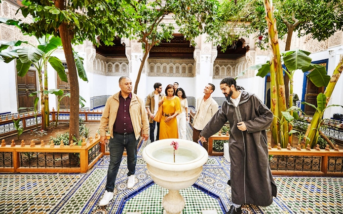 Tourists with a guide in the courtyard of Bahia Palace, Marrakech, Morocco.
