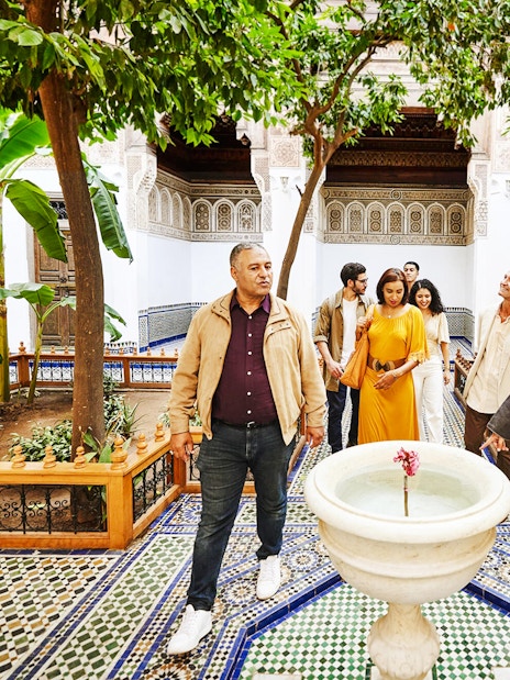 Tourists with a guide in the courtyard of Bahia Palace, Marrakech, Morocco.