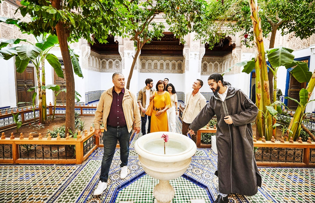 Tourists with a guide in the courtyard of Bahia Palace, Marrakech, Morocco.