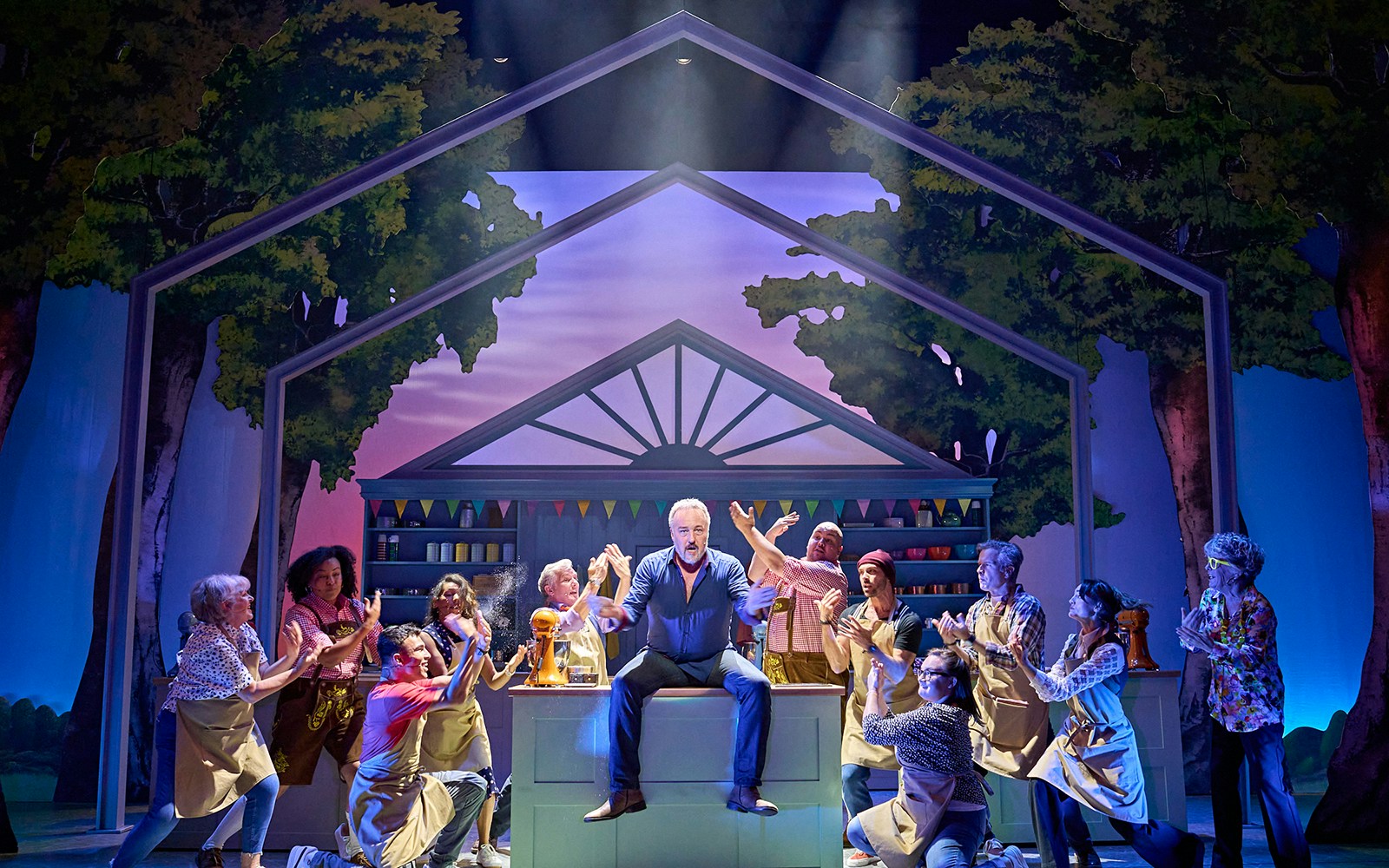 Performers on stage in The Great British Bake Off Musical, with a baking-themed set.
