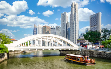 Elgin Bridge over Singapore River with cruise boat and city skyline.