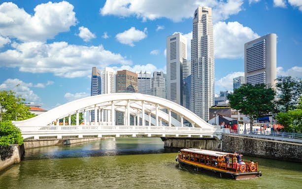 Elgin Bridge over Singapore River with cruise boat and city skyline.