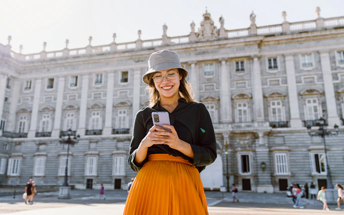 Girl using phone in front of Royal Palace of Madrid.