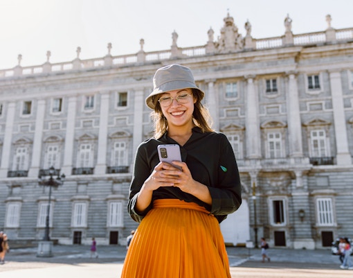 Girl using phone in front of Royal Palace of Madrid.