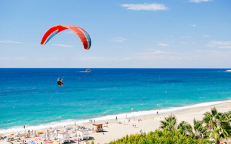 Paragliders soaring over Alanya beach with turquoise sea in the background.