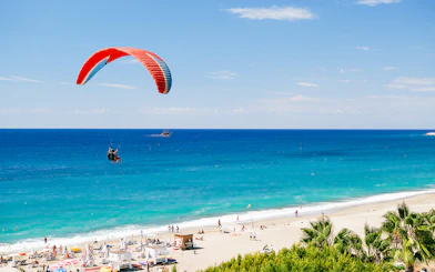 Paragliders soaring over Alanya beach with turquoise sea in the background.