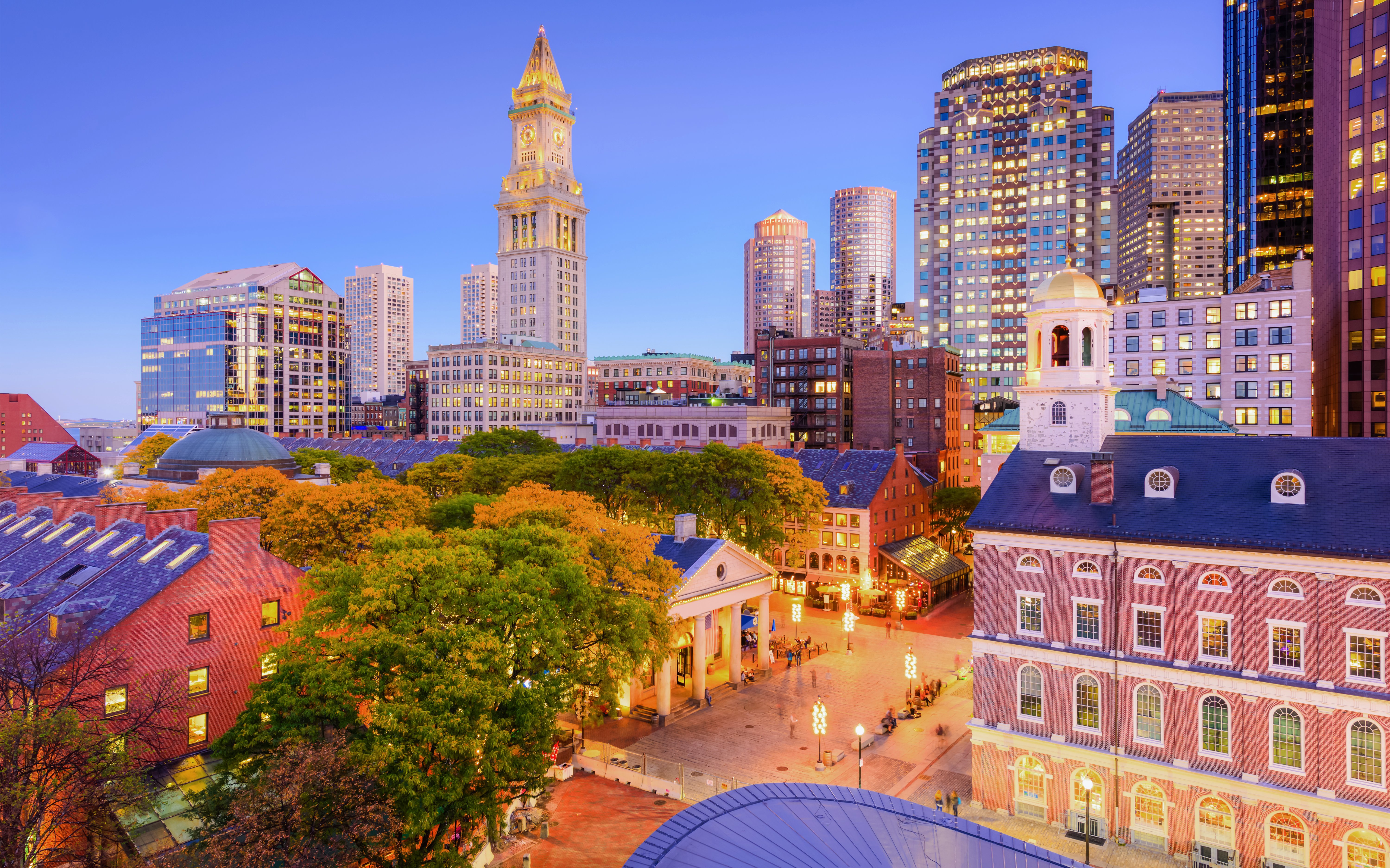 Faneuil Hall Marketplace in Boston with Quincy Market and city skyline at dusk.