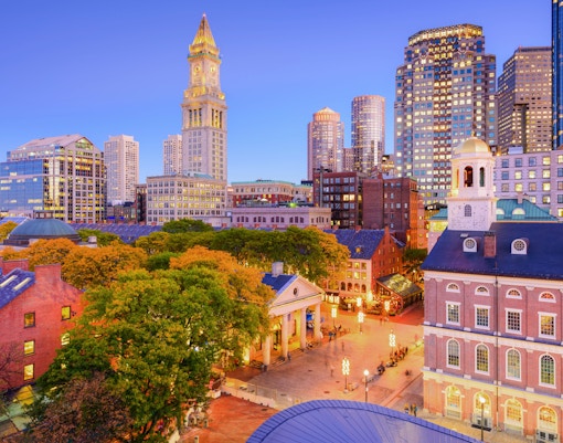 Faneuil Hall Marketplace in Boston with Quincy Market and city skyline at dusk.