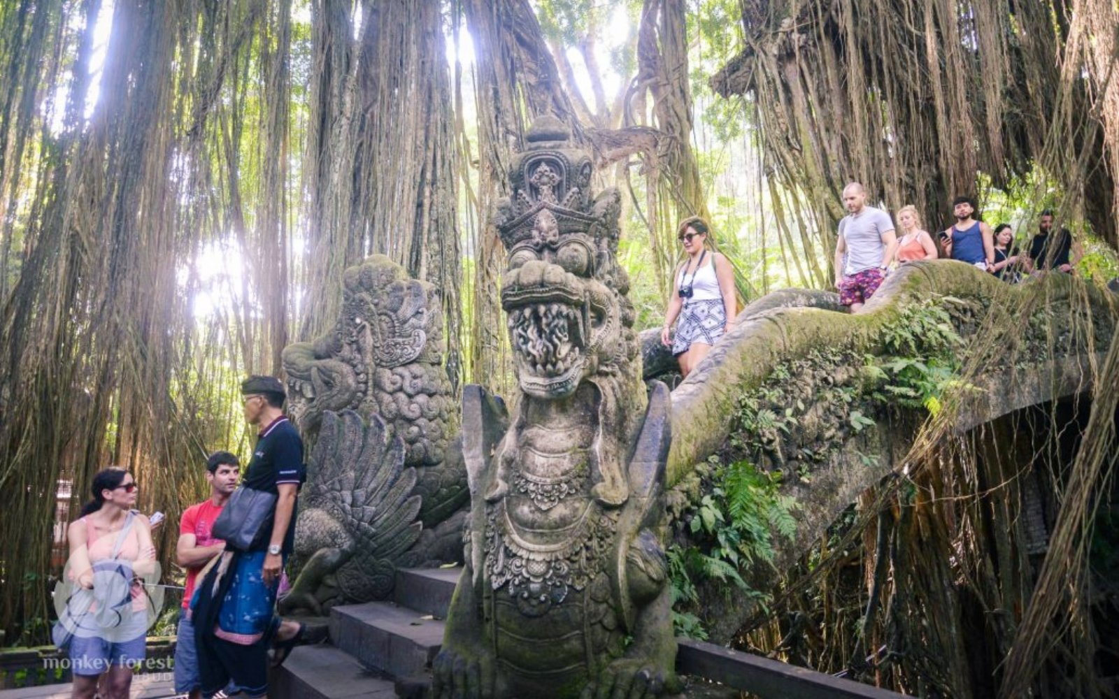 Visitors exploring stone sculptures and lush greenery at Sacred Monkey Forest Ubud.