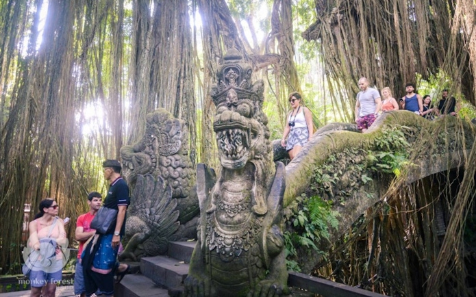 Visitors exploring stone sculptures and lush greenery at Sacred Monkey Forest Ubud.