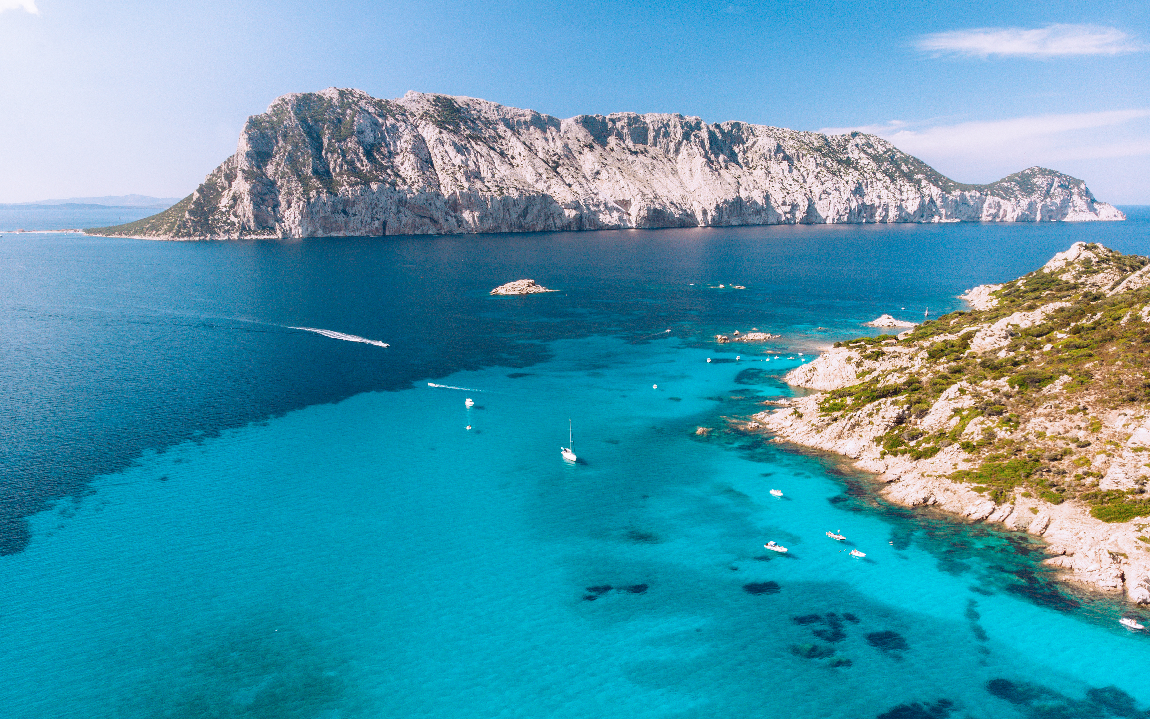 Aerial view of Tavolara Island with boats in turquoise waters, Sardinia, Italy.